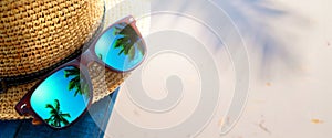 abstract tropical sand beach from above with straw bucket hat and sunglasses, palm trees reflection, summer vacation concept