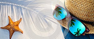 abstract tropical sand beach from above with straw bucket hat and sunglasses, palm trees reflection, summer vacation concept