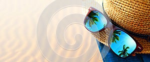 abstract tropical sand beach from above with straw bucket hat and sunglasses, palm trees reflection, summer vacation concept