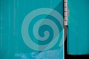 Abstract of turquoise, exterior metal door with chrome hinge