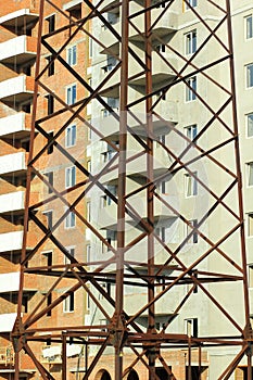 Abstract vertical industrial background of brick multistory building under construction behind close up power lines pylon tower