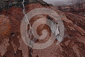 Abstract view of the last restants of snow and ice next to a waterfall of meltwater coming from the gletser of the Chimborazo