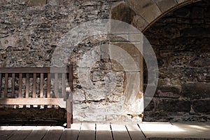 Abstract view of a wooden bench seen within a very old, historical building.