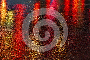 Abstract, wet asphalt road illuminated at night by colorful lights