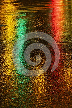 Abstract, wet asphalt road illuminated at night by colorful lights