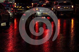 Abstract, wet asphalt road illuminated at night by colorful lights