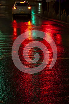 Abstract, wet asphalt road illuminated at night by colorful lights