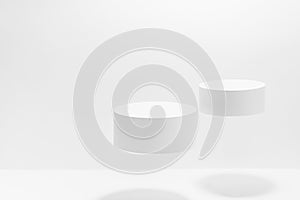 Abstract white scene mockup - two round white cylinder podiums levitate in hard light, shadow.