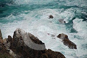 Abstract wild coast line with cliffs and crashing waves, shot from above.