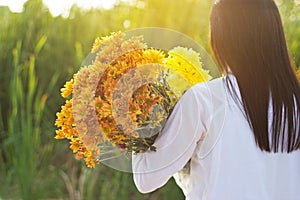 Abstract woman with bouquet flowers vibrant in hands on grass field background