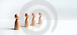 Abstract wooden toy figures stand in a row on a white background. Concept of employees in a team