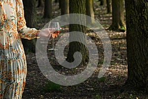 Young woman with Glass of Rose Wine in Forest