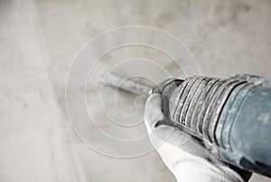 Abstraction photo of noisy repair. electric tool in the hands of a construction worker, gadder against a concrete wall