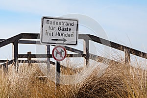 absurd funny sign on a pier, German text, Badestrand fÃÂ¼r GÃÂ¤ste mit Hunden, meaning beach for guests with dogs, on a additional