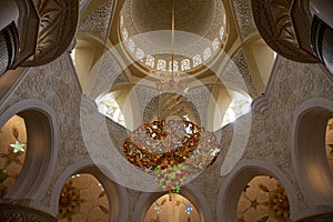 Abu Dhabi, United Arab Emirates. Elegant Modern Lamp Hanging in Inner courtyard and Night view of Sheikh Zayed Grand Mosque (