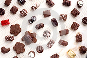 Abundance of chocolates on a light wooden background close up