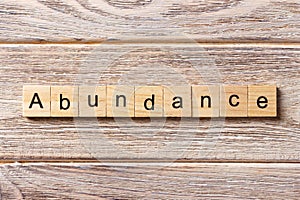 Abundance word written on wood block. abundance text on table, concept photo