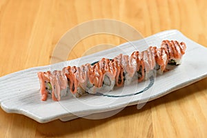 Aburi Sake Mentai Roll with cheese in white dish side view on wooden background
