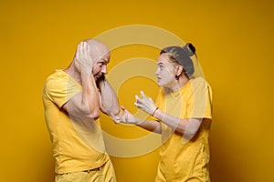 Abuse. Furious woman screams and scolds the man who, in fear, covered his ears with his hands. Domestic violence concept