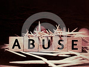 ABUSE text on wooden blocks in dark grungy background.