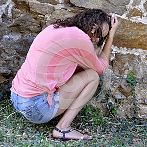 Abused and frightened woman sitting in the corner of a derelict