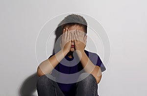 Abused little boy closing eyes near white wall. Domestic violence concept