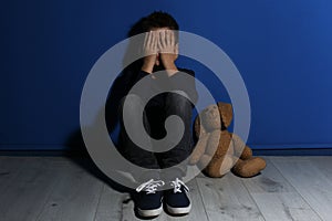 Abused little boy crying near wall. Domestic violence concept
