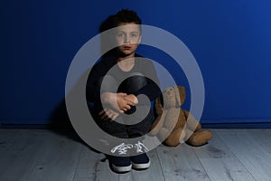 Abused little boy with toy near wall. Domestic violence concept