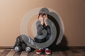 Abused little girl crying near wall. Domestic violence concept