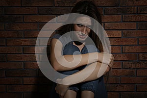 Abused young woman crying near wall. Domestic violence concept