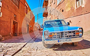 ABYANEH, IRAN - OCTOBER 23, 2017: The vintage blue car is parked in medieval street of historic mountain village, on October 23 in