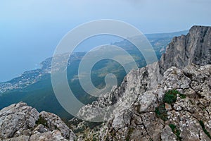 Abyss in steep rocks Ai-Petri, Crimea. Cliff against the backdrop of blue coastline with city and forest, beautiful summer