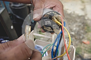 An AC technician removes a defective capacitor from a window type air conditioner control panel
