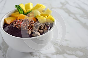 acai bowl garnished with tropical fruit toppings on marble
