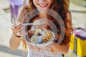 Acai bowl woman eating morning breakfast at cafe. Closeup of fruit smoothie healthy diet for weight loss with berries and oatmeal.