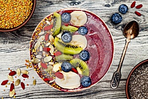 Acai breakfast superfoods smoothies bowl with chia seeds, bee pollen, goji berry toppings and fruits. Overhead. top view, flat lay