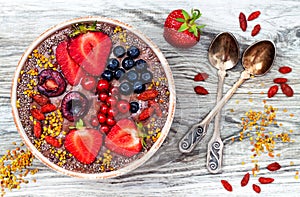 Acai breakfast superfoods smoothies bowl with chia seeds, bee pollen, goji berry toppings and peanut butter. Overhead photo