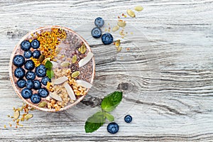 Acai breakfast superfoods smoothies bowl topped with chia, flax and pumpkin seeds, bee pollen, granola, coconut and blueberries