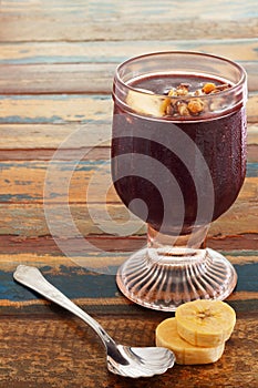 Acai in glass with banana on wooden table