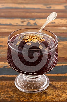Acai in glass with muesli on wooden table. Vertical