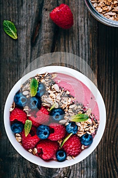 Acai smoothie and granola bowl with fresh raspberries and blueberries