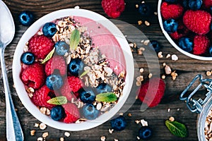 Acai smoothie and granola bowl with fresh raspberries and blueberries