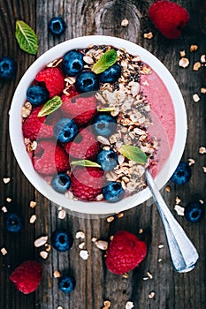 Acai smoothie and granola bowl with fresh raspberries and blueberries