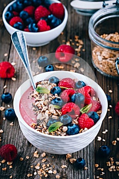 Acai smoothie and granola bowl with fresh raspberries and blueberries