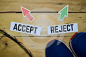 Accept or Reject opposite direction signs with boots, eyeglasse and sneakers on wooden