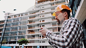 Acceptance of construction works. A man in a hard hat holds a construction plan in the phone. The man checks the conformity of the