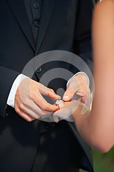 Accepting a token of his love. Cropped image of a groom putting the ring on his brides finger on their wedding day.