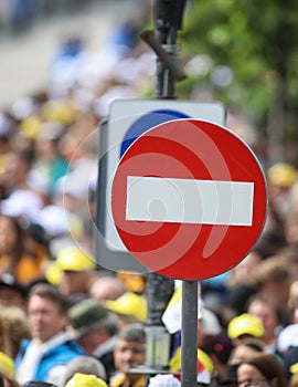 Access denied road sign with a large mass of people in the background - social or mass control