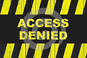 Access denied warning sign with yellow and black stripes painted over cracked wood.