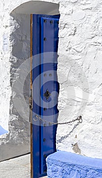 Access door to windmill in Consuegra, Toledo, Castilla La Mancha, Spain. A chain holds the intense blue door so that the wind does photo